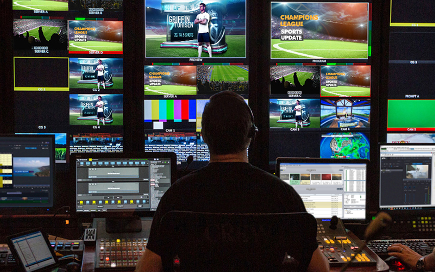 News operator in control room managing multiple sports graphics and live feeds